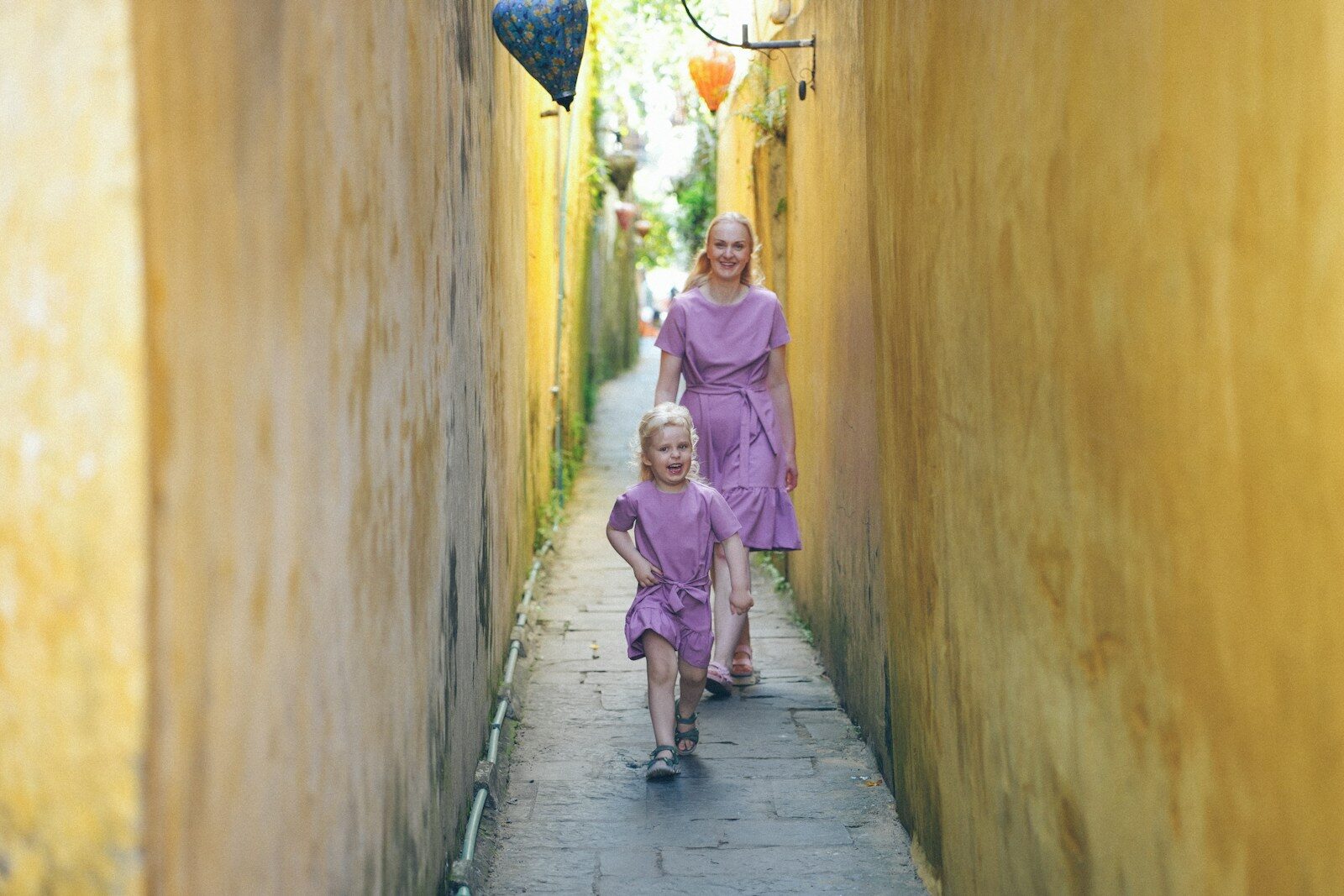 Two women walk down a narrow alleyway.